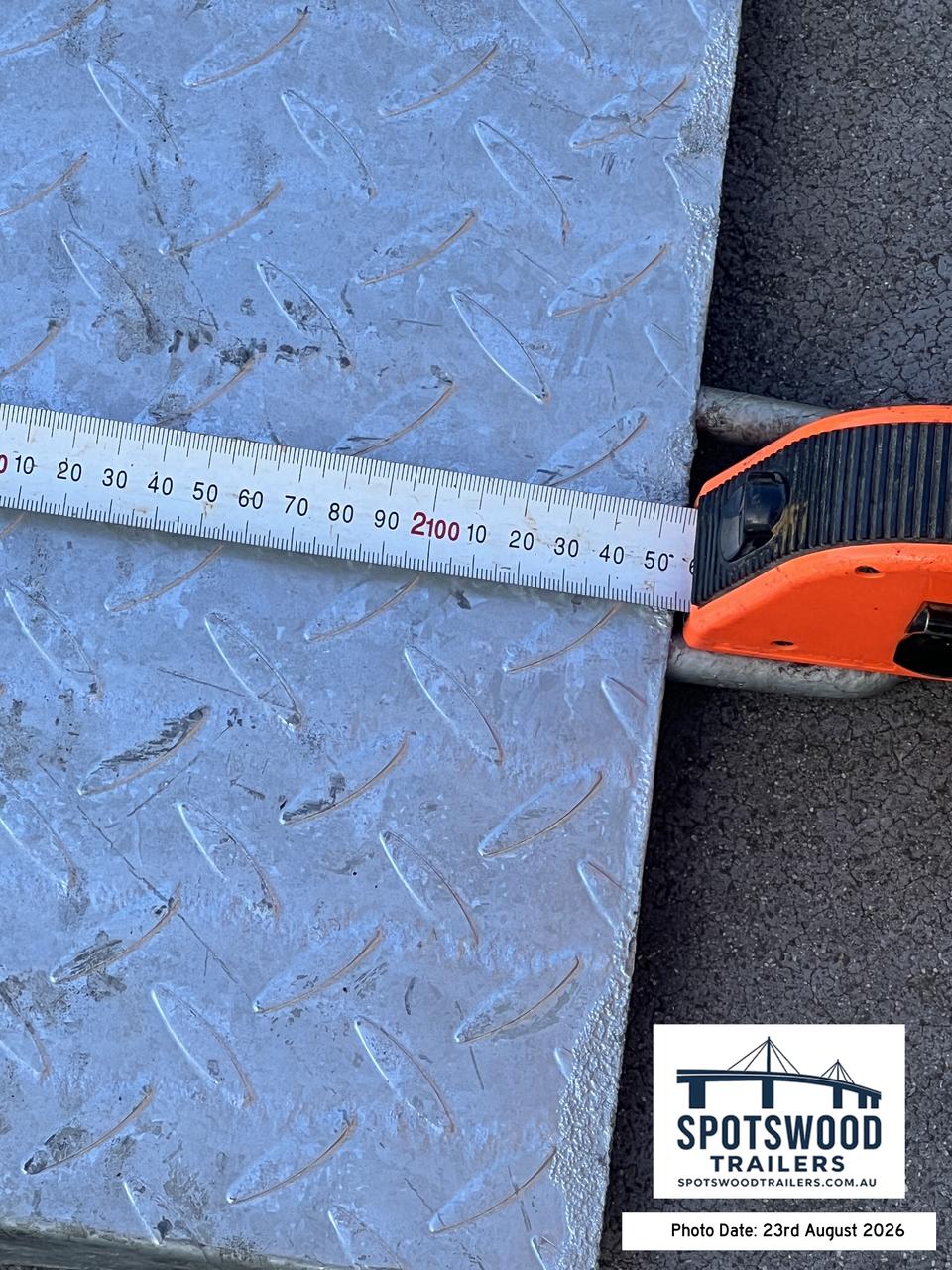 Close-up tape measurement of The Deckhand checkerplate trailer loading ramp width