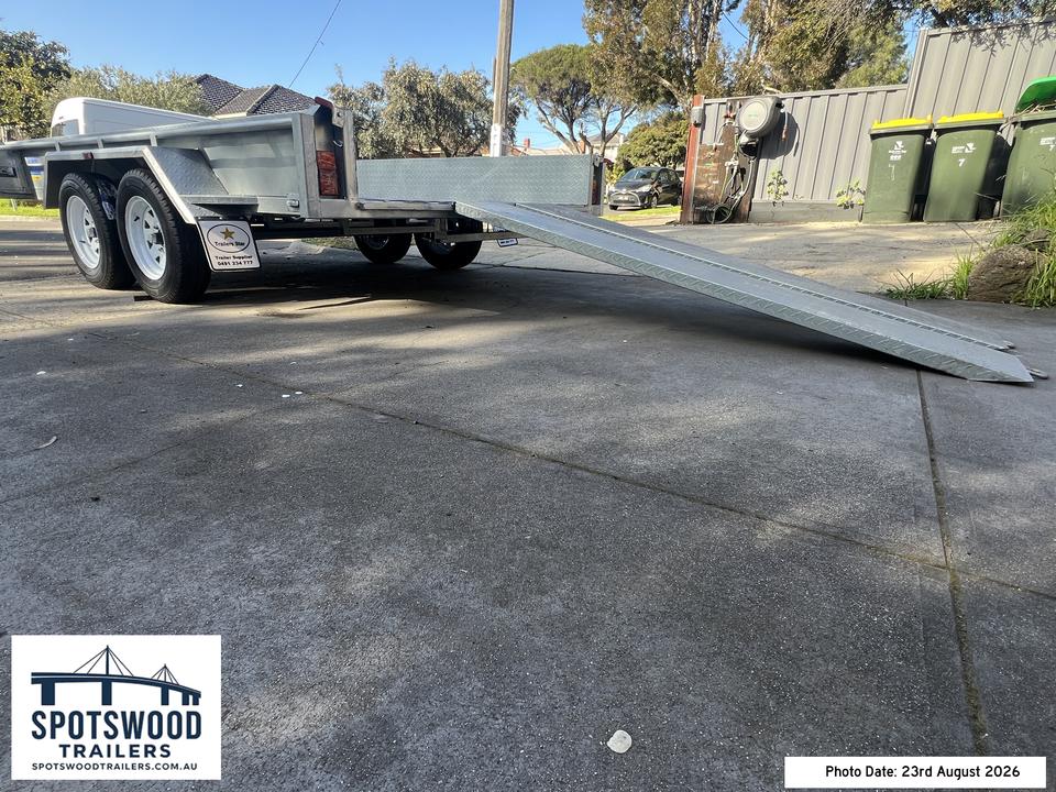 Low angle side view of twin loading ramps attached to the rear of a 12x6 flat-top trailer