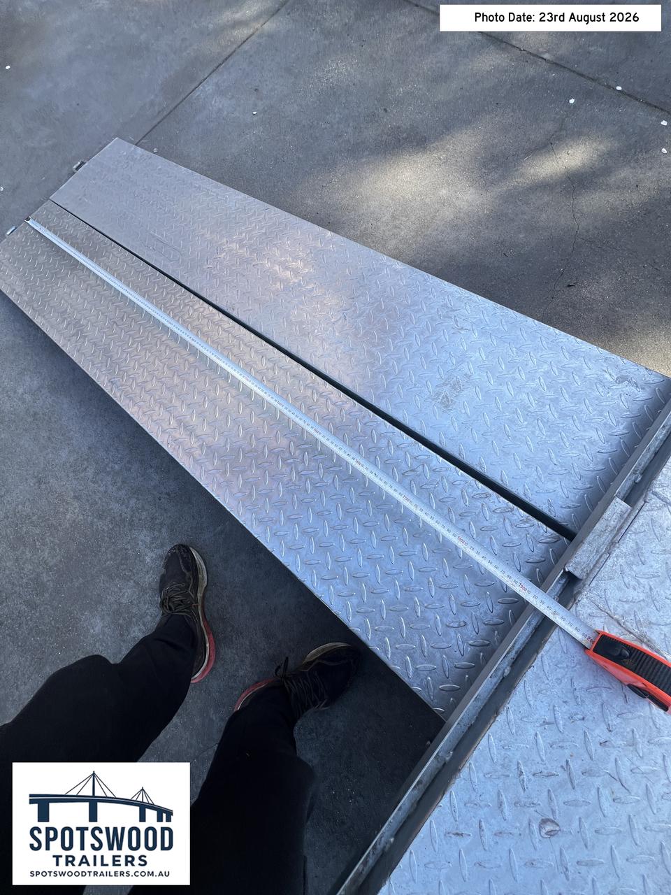 Twin trailer loading ramps positioned together with tape measurement showing their combined loading width